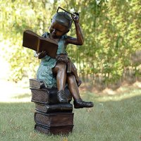 Mädchen mit Brille sitzt auf Bücherstapel und liest aus Bronze - Tilly von Gartentraum.de