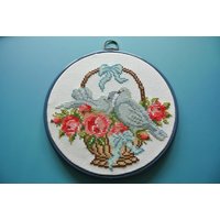 Vintage 1980S Größere Runde Kreuzstich Stickerei Mit Mehrfarbiger Blume/ Tauben Im Korb Motiv Wandbehang, Weiße Baumwolle, Blauer Kunststoffrahmen Vintage 1980S Größere Runde Kreuzstich Stickerei Mit Mehrfarbiger Blume/ Tauben Im Korb Motiv Wandbehang, Weiße Baumwolle, Blauer Kunststoffrahmen von NORDICARTLINENS