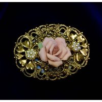 Eine Filigrane Brosche Mit Einer Rosenknospe Aus Keramik, Die Auf Einem Blauen Ovalen Salzstreuer Montiert Ist von PatternsInNature