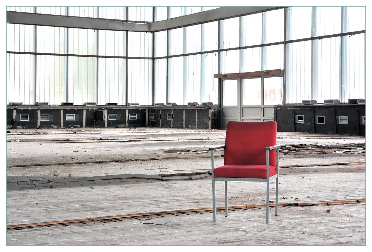 Wallario Küchenrückwand Stille und Leere - ein einsamer roter Stuhl in einer alten Halle, (1-tlg) von Wallario