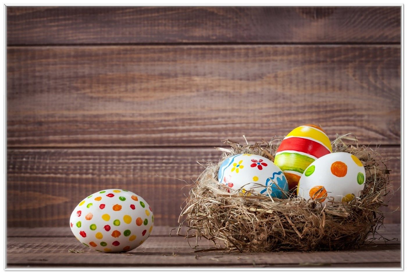 Wallario Poster, Bunte bemalte Eier an Ostern im Vorgelnest vor hölzerner Wand, in verschiedenen Ausführungen von Wallario