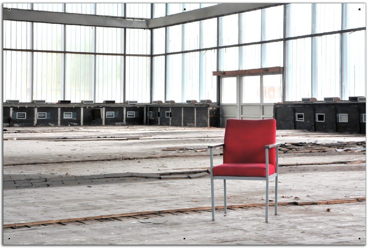Wallario Sichtschutzzaunmatten Stille und Leere - ein einsamer roter Stuhl in einer alten Halle von Wallario